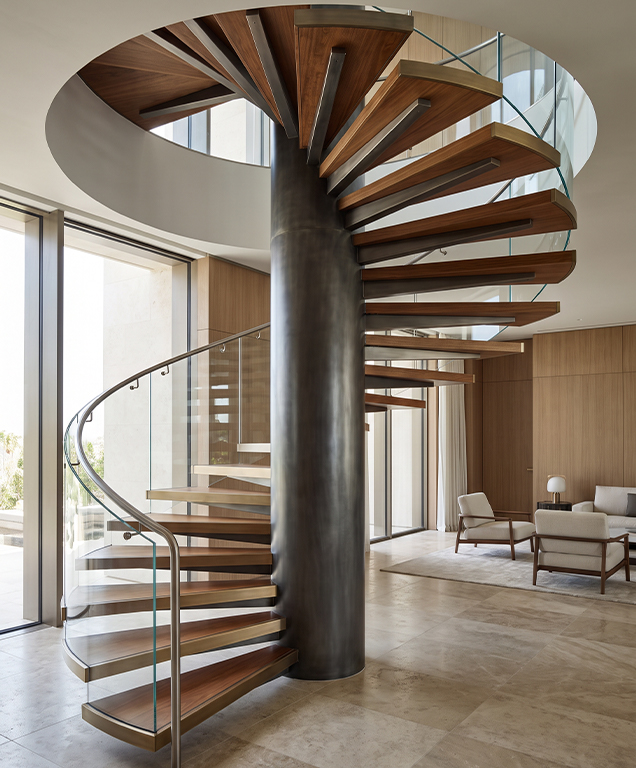 Escalier colimaçon à noyau central avec marches en bois et garde-corps en verre dans une villa contemporaine