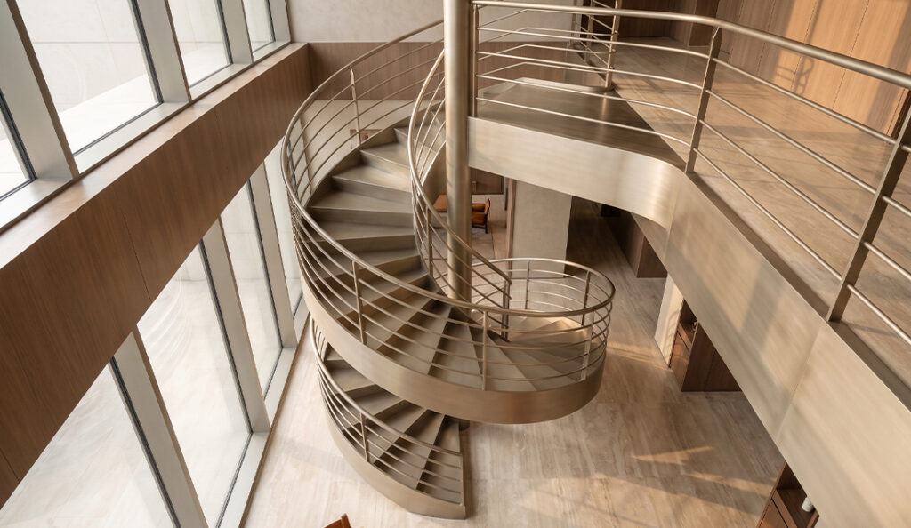 Escalier colimaçon métallique vu depuis le haut avec marches courbes et garde-corps horizontal